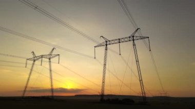 Güneş doğarken elektrik hatları olan yüksek voltajlı kulelerin koyu gölgesi..