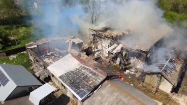Çökmüş çatısı ve yükselen karanlık dumanı olan yıkık binanın havadan görünüşü.