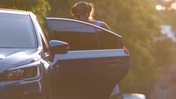 Sopir Wanita Muda Mengambil Koper Hijau Keluar Dari Mobilnya Berjalan — Stok Video