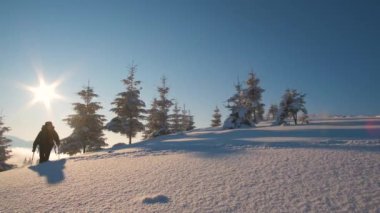 Sırt çantalı bir yürüyüşçü soğuk kış gününde karlı dağ yamacında yürüyor..