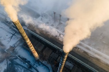 Kömür santralinin hava manzarası siyah dumanlı yüksek borular gün batımında atmosferi kirletiyor.