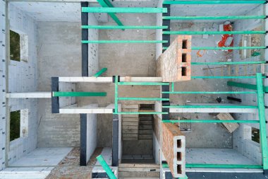 Havalandırılmış hafif beton duvarları ve inşaat halindeki ahşap çatı kirişleri olan bitmemiş özel evin havadan görüntüsü..