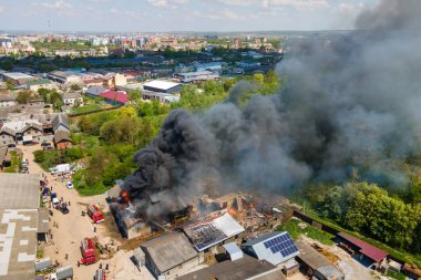 İtfaiyecilerin yıkık dökük çatısı ve yükselen kara dumanlı yangını söndürme görüntüsü..