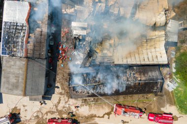 İtfaiyecilerin yıkık dökük çatısı ve yükselen kara dumanlı yangını söndürme görüntüsü..