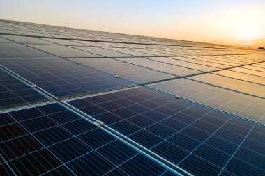 Mavi fotovoltaik güneş panelleri gün batımında temiz ekolojik elektrik üretmek için çatıya monte edildi. Yenilenebilir enerji konsepti üretimi.