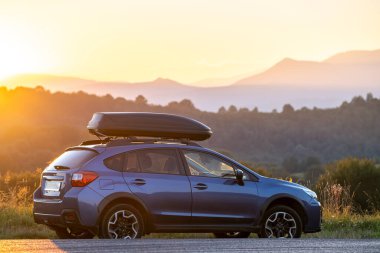 Gün batımında yol kenarına park edilmiş, çatı rafı konteynırlı arazi aracı. Yolculuk ve kaçış konsepti.