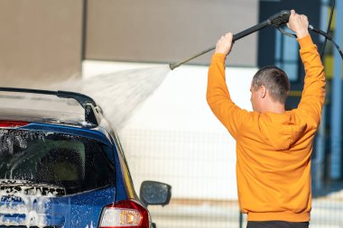 Genç şoför arabasını yüksek basınçlı su jeti ile yıkıyor..