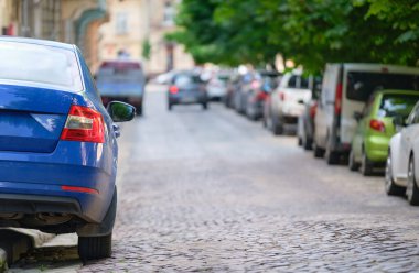 Şehrin caddesine park etmiş bir arabanın yakınına..