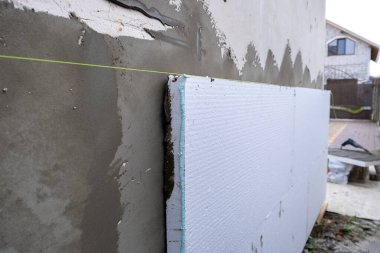 Termal koruma için ev cephesi duvarına köpük yalıtım çarşafları kurulumu.