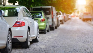 Sokak kenarında park halindeki arabalarla şehir trafiği.