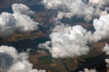 Parlak güneşli bir günde beyaz bulutların uçak penceresinden hava manzarası.