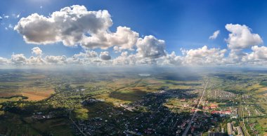 Uzak şehrin yüksek irtifasındaki uçak penceresinden hava manzarası beyaz kabarık kümülüs bulutlarıyla kaplı..