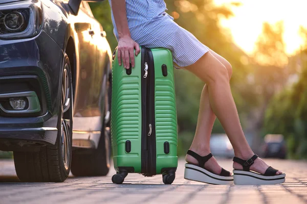 車の横にあるスーツケースの袋に座っている若い女性のスリムな足の閉鎖 旅行や休暇のコンセプト — ストック写真