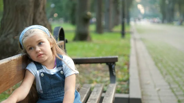 Klein Serieus Kind Meisje Zit Alleen Een Bank Zomer Park — Stockfoto