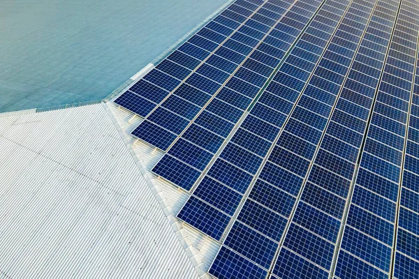 Aerial view of surface of blue photovoltaic solar panels mounted on building roof for producing clean ecological electricity. Production of renewable energy concept.