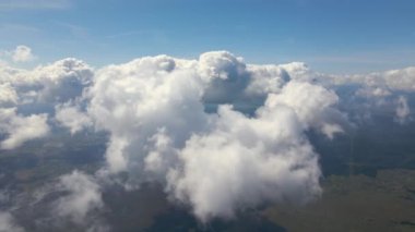 Dünya 'nın yüksek irtifasındaki uçak penceresinden hava manzarası beyaz kabarık kümülüs bulutlarıyla kaplı..