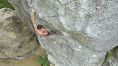 Güçlü erkek tırmanıcı kayalık dağın dik duvarına tırmanıyor. Sporcu zor yolu aştı. Ekstrem spor hobisi konsepti.