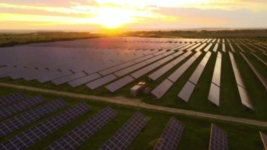 Günbatımında temiz ekolojik elektrik enerjisi üretmek için sıra sıra güneş fotovoltaik panelleri olan sürdürülebilir büyük elektrik santralinin havadan görünüşü. Sıfır emisyon kavramı ile yenilenebilir elektrik.