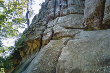 Kararlı bir çocuk kayalık dağın dik duvarına tırmanıyor. Çocuk zor yolu aşıyor. Ekstrem sporlar ve kaya tırmanışı hobileri..