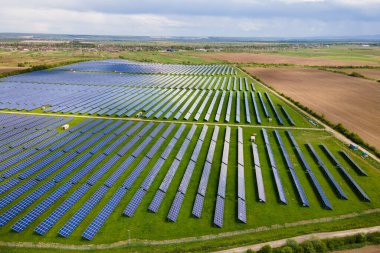 Temiz ekolojik elektrik enerjisi üretmek için birçok sıra güneş fotovoltaik paneli bulunan sürdürülebilir büyük elektrik santralinin havadan görünüşü. Sıfır emisyon kavramı ile yenilenebilir elektrik.