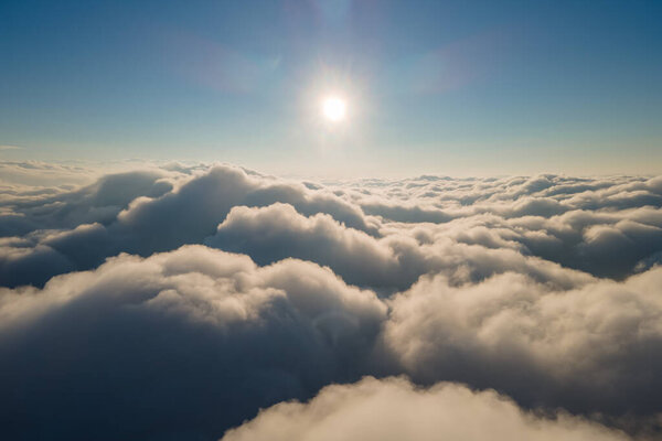 Aerial view from airplane window at high altitude of dense puffy cumulus clouds forming before rainstorm in evening.