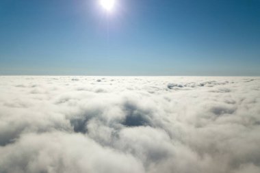 Parlak güneşli bir günde, beyaz kabarık bulutların yukarıdan görünüşü.