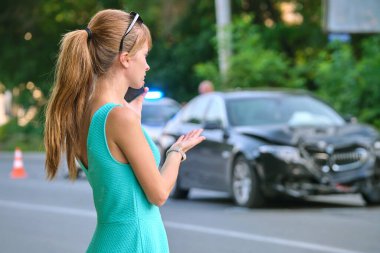 Üzgün kadın sürücü cadde tarafında cep telefonuyla konuşuyor. Araba kazasından sonra acil servisi arıyor. Yol güvenliği ve sigorta kavramı.