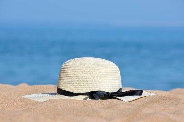Sıcak güneşli bir günde, tropikal deniz kıyısındaki kumlu plajda sarı hasır şapka. Yaz tatili kavramı.