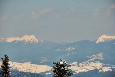 Soğuk kış günlerinde yoğun kar yağışı sonrası yüksek dağlık tepelerle kaplanmış kış manzarası..