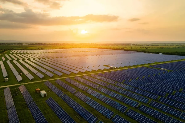 Aerial view of large sustainable electrical power plant with many rows of solar photovoltaic panels for producing clean ecological electric energy in evening. Renewable electricity with zero emission concept.