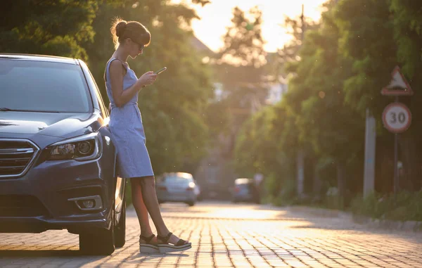 Молодая Женщина Водитель Стоящая Возле Своего Автомобиля Просматривает Мобильный Телефон — стоковое фото