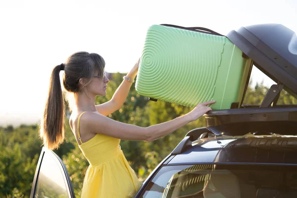 Mujer Joven Poniendo Maleta Verde Dentro Del Portaequipajes Del Coche — Foto de Stock