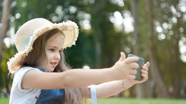 幸せな笑顔子供女の子見てで彼女の携帯電話屋外で夏 — ストック写真
