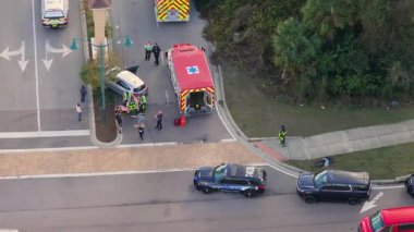 Vehicle collision with emergency technicians assisting victim on stretcher, surrounded by first responders and rescue staff