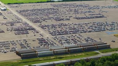 Üretim fabrikasının otoparkında yeni arabalar için uzun yol otomobil rafları. Araçlar krupiye limanında arka arkaya park edilmiş. Otomotiv endüstrisi