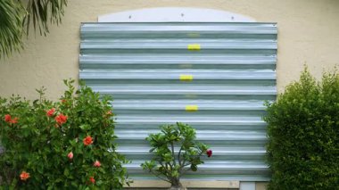 Kasırgalara karşı korunmak için Florida 'daki yerleşim yerlerinin camlarına metal fırtına kepenkleri takıldı. Doğal afetten önce önleyici güvenlik önlemi.