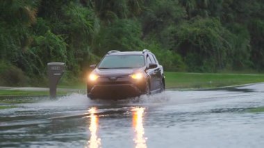 Florida 'nın kenar mahalleleri sel felaketinin ardından sular altında kaldı. Arabalar ihtiyatlı bir şekilde yerleşim bölgelerinde yüksek sularda ilerliyorlar.
