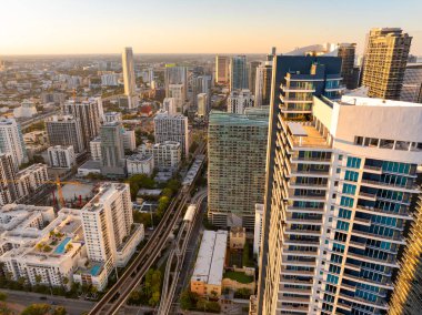 Miami Brickell 'in hava sahnesi demiryolunu yükseltti ve uzun binalar ve Florida, ABD' de gün batımı arasında banliyö trenini geçti..