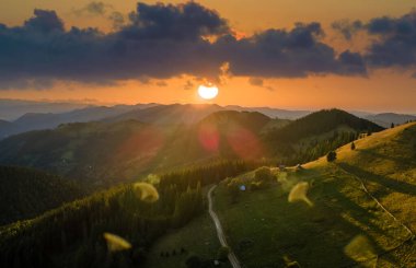Yamaçta eski çoban evi olan vahşi dağ ormanlarında gün batımı manzarası inanılmaz. Parlak batan güneşle aydınlatılmış karanlık çam ağaçları. Güzel doğa manzarası.