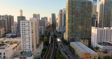 Miami Brickell 'in hava sahnesi demiryolunu yükseltti ve uzun binalar ve Florida, ABD' de gün batımı arasında banliyö trenini geçti.