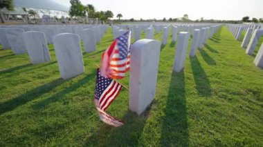 Sarasota Ulusal Mezarlığı 'nda bir sürü beyaz mezar taşı ve yeşil çimlerde Amerikan bayrağı var. Anma Günü konsepti