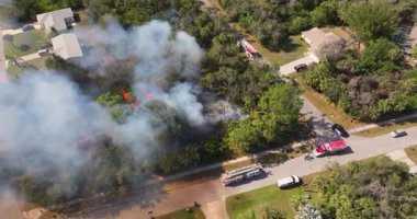 Acil durum ekipleri ve itfaiye araçları Florida 'daki evlerin yakınındaki bitki örtüsü yangınlarına tepki veriyor, sakinleri ve mülkleri korumak için alevlerle mücadele ediyorlar..