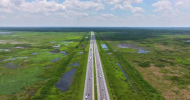 Florida I-75 koridoru Everglades 'e benzeyen sulak alanlardan geçiyor. Direkt güneş altında, araçlar ve yarı kamyonlarla birlikte.