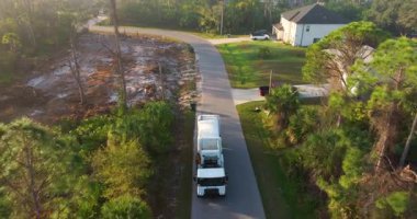 Çöp kamyonu Amerikan mahallesinin kaldırımından çöp kutusu yüklüyor.