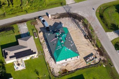 İnşaat işçileri çatıya asfalt kiremitler seriyorlar. Özel evin çatısı açıkta. Florida ev yapımı projesi.