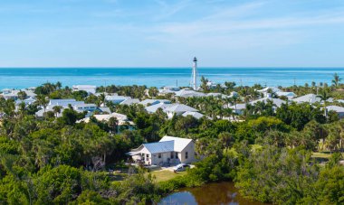 Florida 'nın güneybatısındaki Boca Grande adasındaki yeşil palmiye ağaçları arasında pahalı malikaneler. Ticari gemiler için deniz kıyısındaki beyaz deniz feneri..