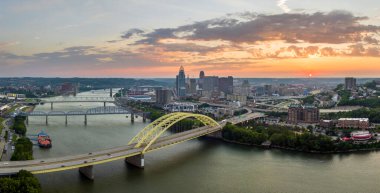 Ohio, Cincinnati 'de trafik Daniel Carter Sakal Köprüsü' nde şehir merkezindeki yüksek gökdelen binalarıyla aydınlandı. Gün batımında finans bölgesi olan Amerikan şehri.