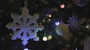 Geceleri Noel ağacı dalları renkli mücevherler, kurdeleler ve yanıp sönen ışıklarla kaplanarak zengin ve neşeli bir zemin oluşturur.