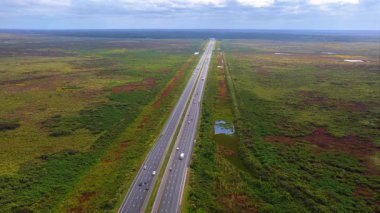 Florida sulak alanındaki otoyolun düz bölümü çimenli su kanalları ve sürüş trafiği ile çevrili.