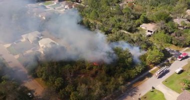 İtfaiyeciler Florida ormanlarında hızla yayılan bir yangınla mücadele ediyor. Banliyö evlerinin yakınındaki itfaiye araçları yerleşim yerlerinin yakınında konuşlanmış durumda.